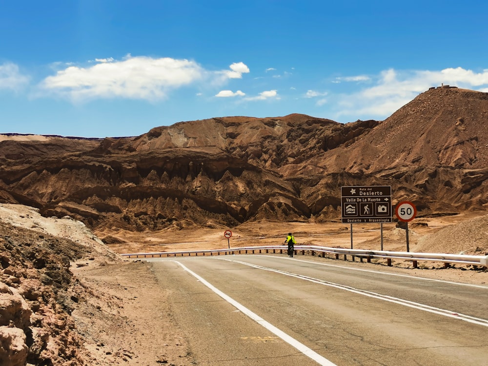 a person riding a bicycle on a road in the mountains