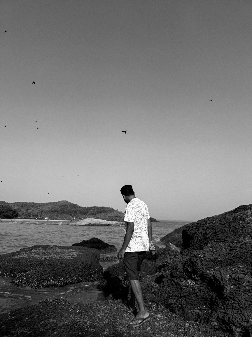 Ein Mann steht an einem felsigen Strand
