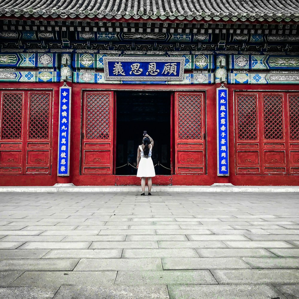 a person standing in front of a building with red doors