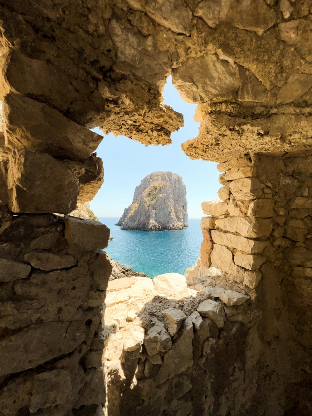 a view of a blue sea through a stone archway