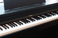 A sleek modern digital piano displayed with headphones and sheet music.