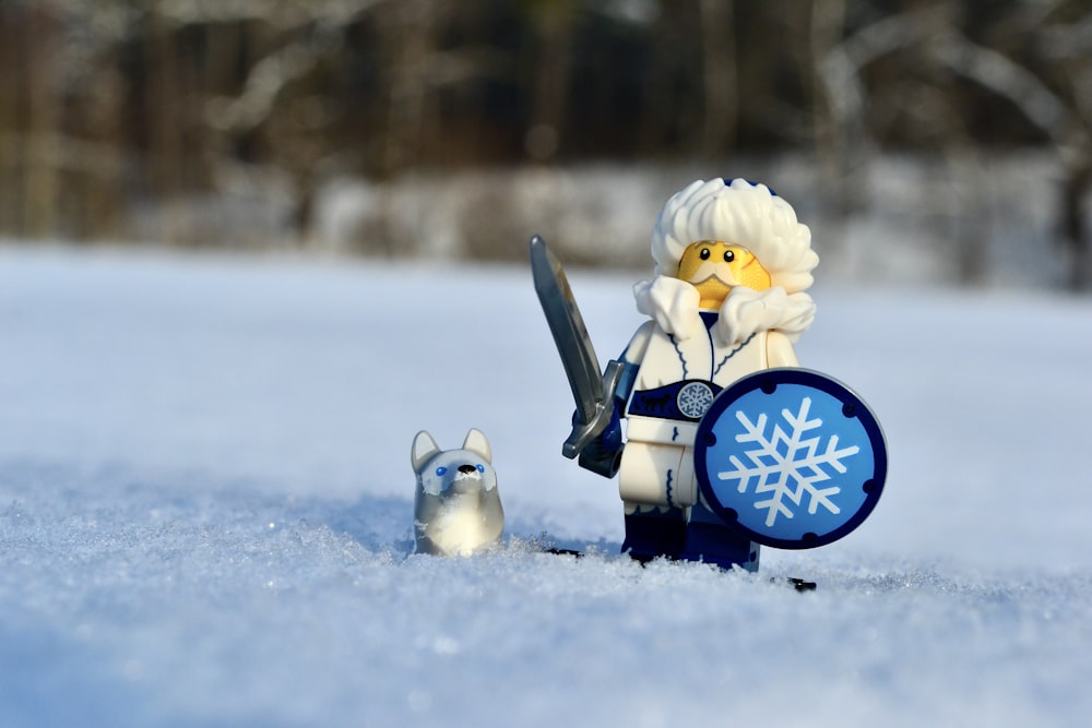 a toy robot with a shield and sword in the snow