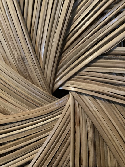 Close-up of an intricate woven pattern made from natural materials, possibly bamboo or rattan, featuring a radial design with overlapping strips.