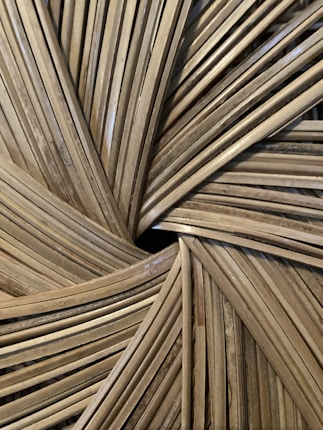 Close-up of an intricate woven pattern made from natural materials, possibly bamboo or rattan, featuring a radial design with overlapping strips.