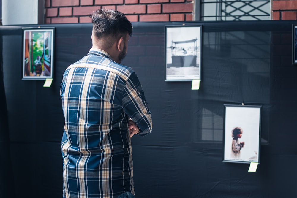 a man looking at pictures on a wall