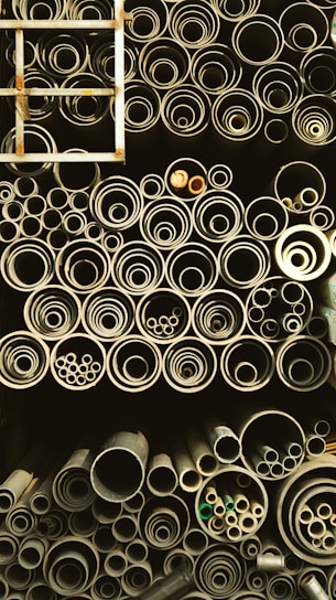 A collection of various mild steel pipes stacked neatly in a warehouse.