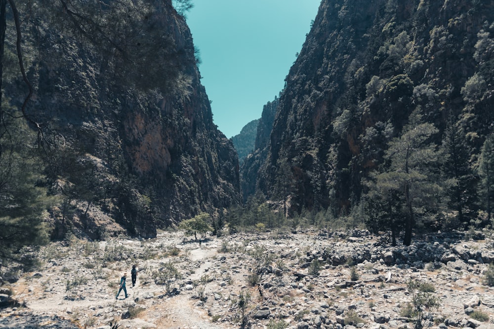 people walking on a dirt path between mountains with Samariá Gorge in the background