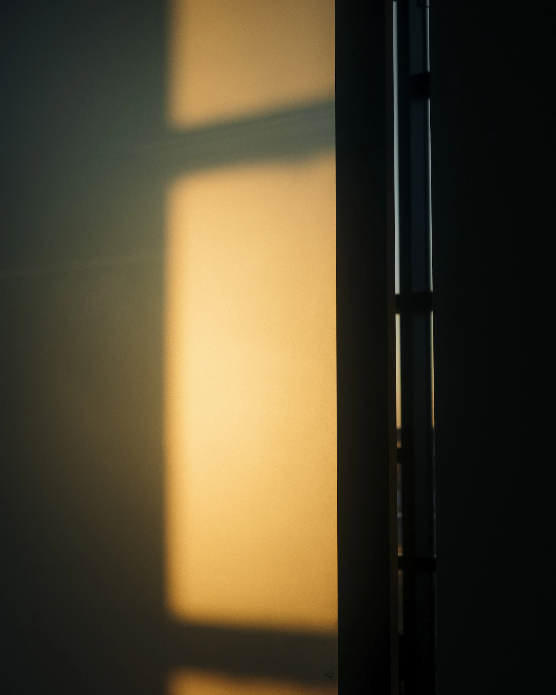 A minimalist shot of a sunlit window casting geometric patterns on a simple white wall, highlighting calm and clarity.