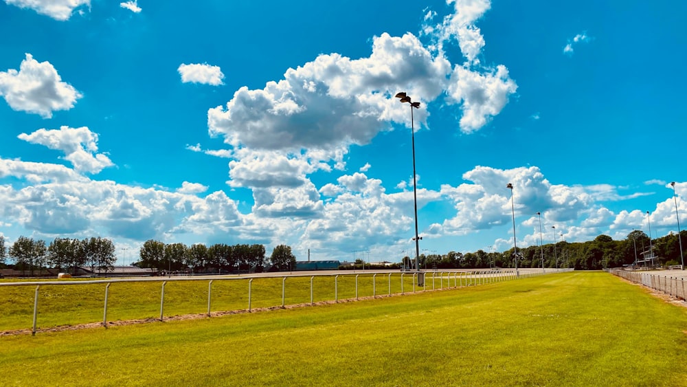 a large green field with a fence and a light post