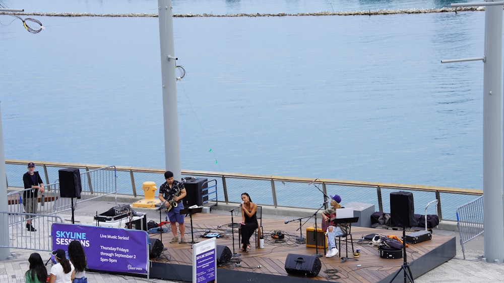 a group of people playing instruments on a stage by a body of water