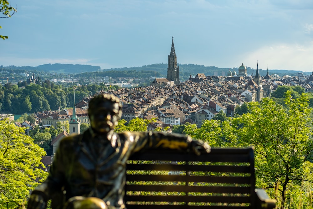 a statue of a person on a bench overlooking a city