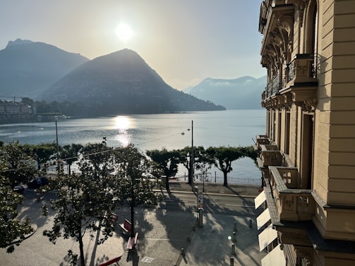 A peaceful lakeside view with joggers and children playing nearby in the early morning light.