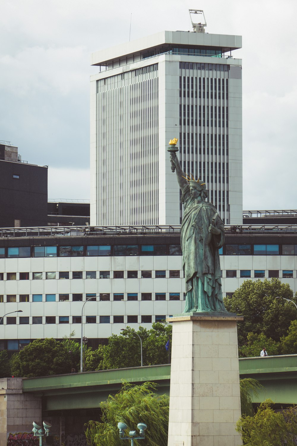 eine Statue einer Person, die eine Fackel vor einem Gebäude hält