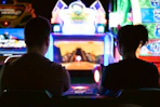 a couple of men sitting in a room with a large screen