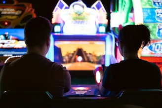a couple of men sitting in a room with a large screen