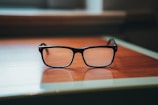 A close-up of elegant eyeglasses resting on a wooden table.