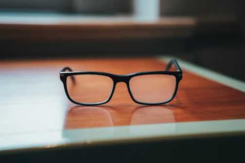 Close-up of elegant eyeglasses displayed on a wooden table with soft lighting