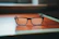 Close-up of a pair of elegant eyeglasses resting on a wooden counter with soft lighting.