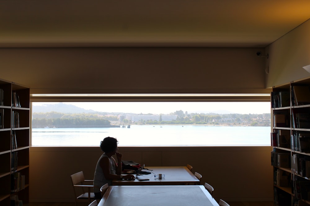 a person sitting at a desk in a room with a window