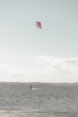 A beginner practicing kitesurf on calm shallow waters with instructor guidance.