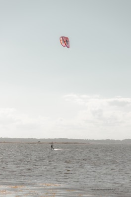 A beginner practicing kitesurf on calm shallow waters with instructor guidance.