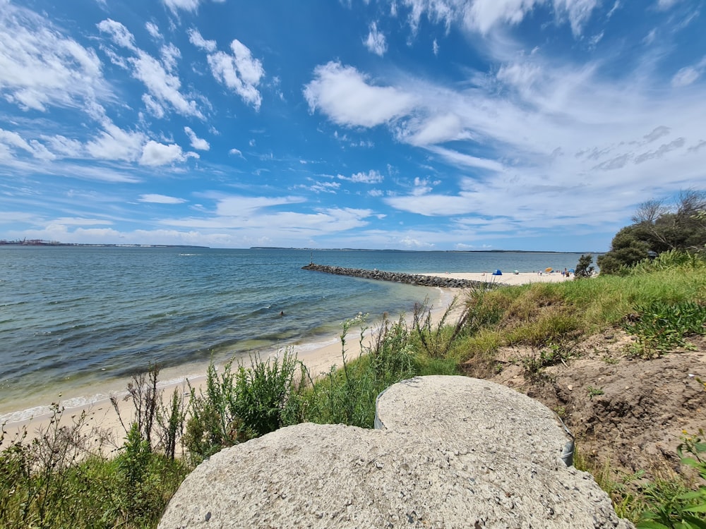 a rocky beach with a body of water in the background