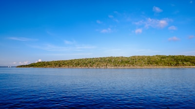 A serene view of the Azores coastline with lush greenery and volcanic cliffs under a clear sky.