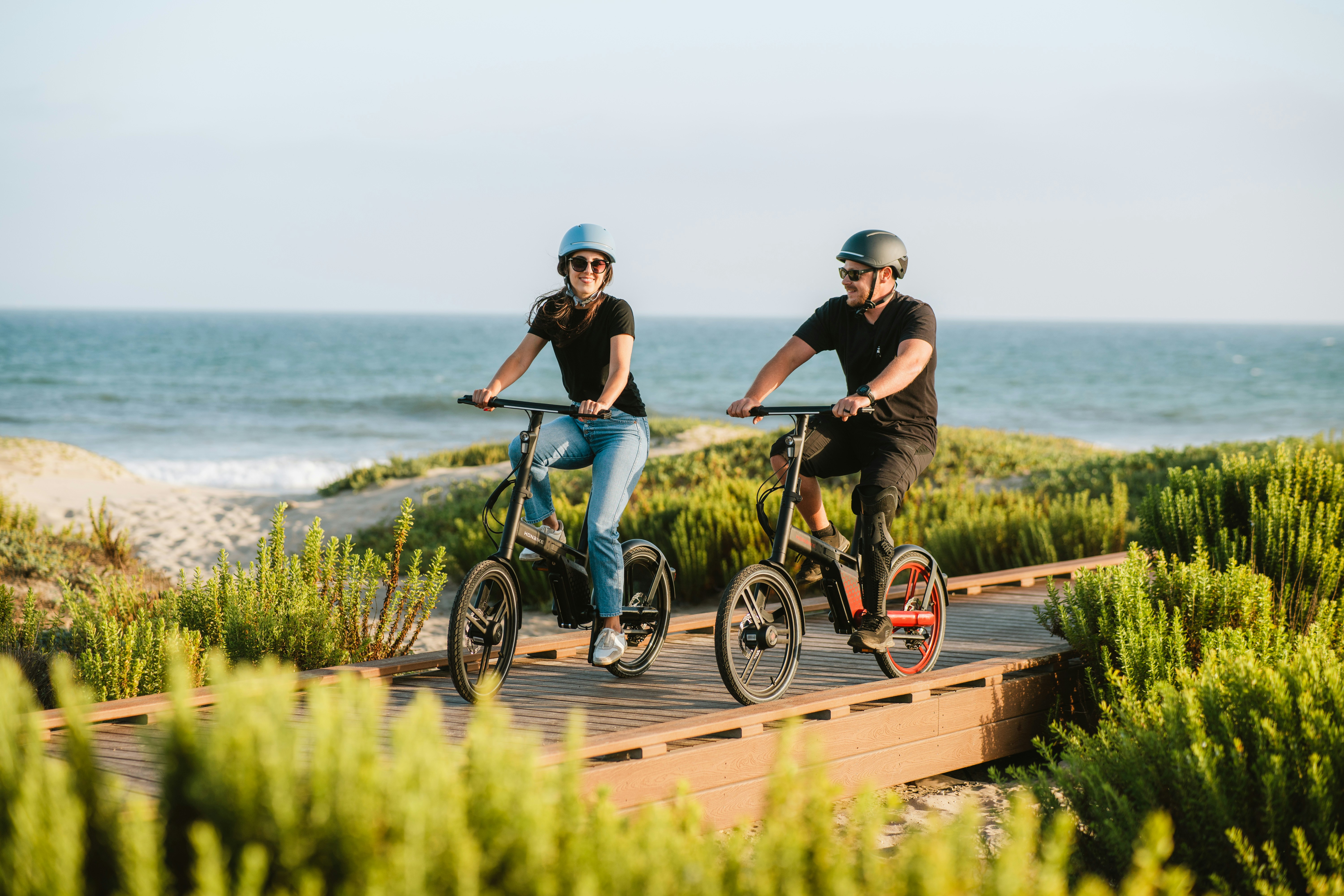 a man and woman riding bikes on a path by the water