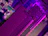 Close-up of a high-end gaming motherboard illuminated by neon purple lighting.