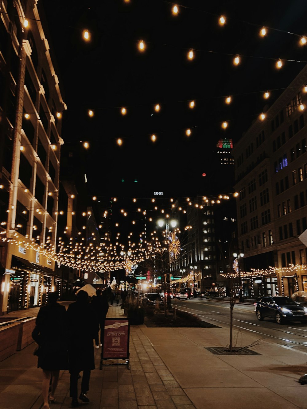 people walking on a sidewalk in a city at night