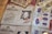 An array of identification documents is spread out. The prominent item in the center is an identity card from a fictional organization named 'Ministry of Magic', featuring a photograph of a smiling person and various personal details. Other documents include fingerprints, currency notes, and tickets. The documents have a vintage and magical theme.