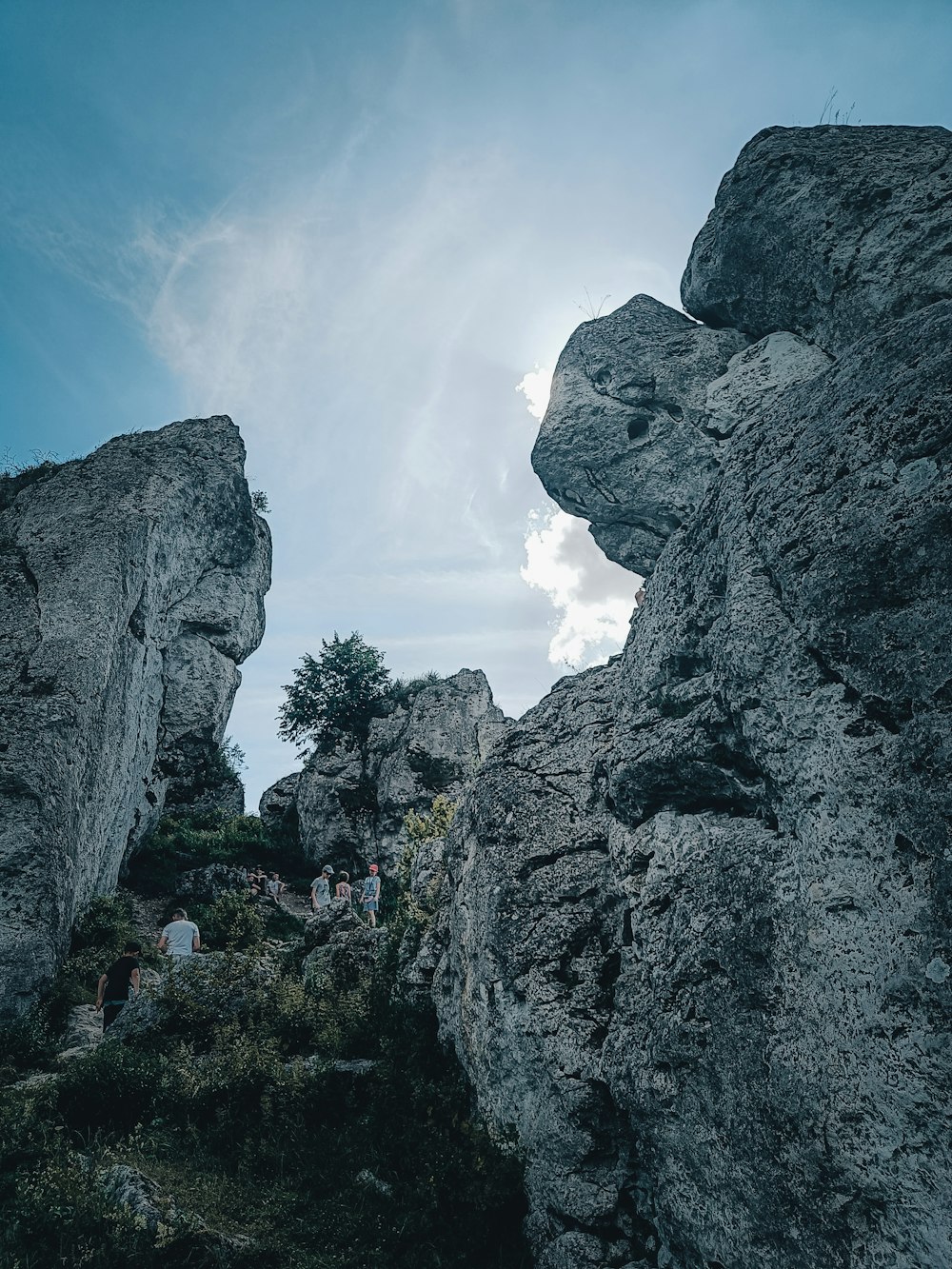 a group of people walking on a path between large rocks