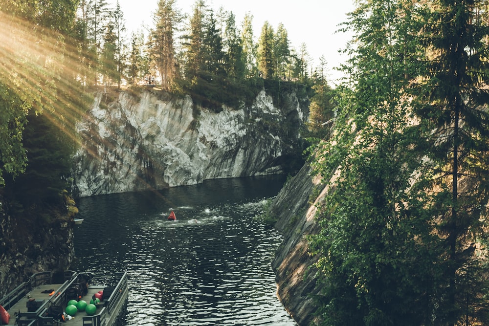 a river with a boat and a cliff with trees on the side