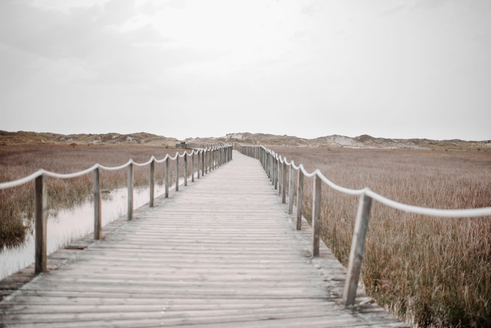 a wooden bridge over a sandy beach