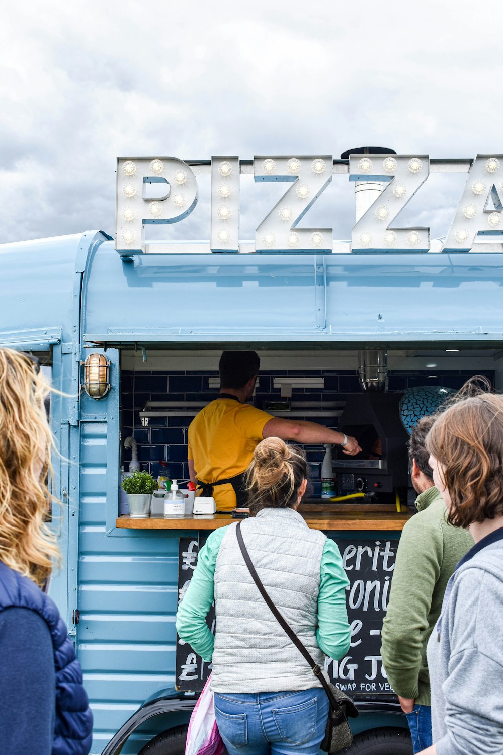 a group of people stand outside a food truck