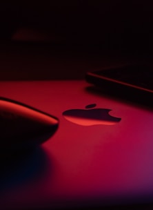 Sleek close-up of a glowing neon green Apple device being carefully repaired on a dark glass surface.
