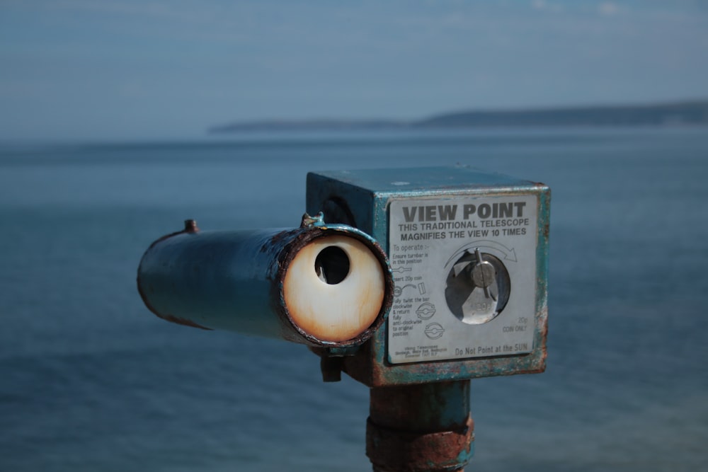 a metal object with a sign on it by the water