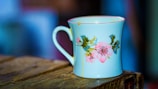Artistic photo of a personalized mug with delicate floral design on a wooden table.