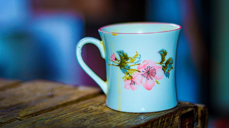 Artistic photo of a personalized mug with delicate floral design on a wooden table.
