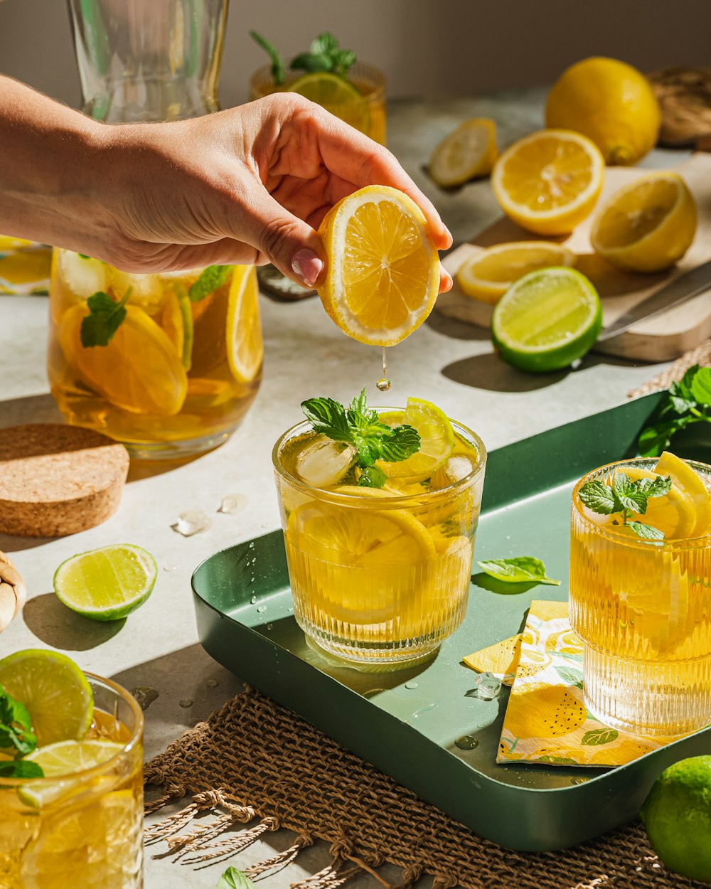 a hand holding a lemon over a glass of lemonade