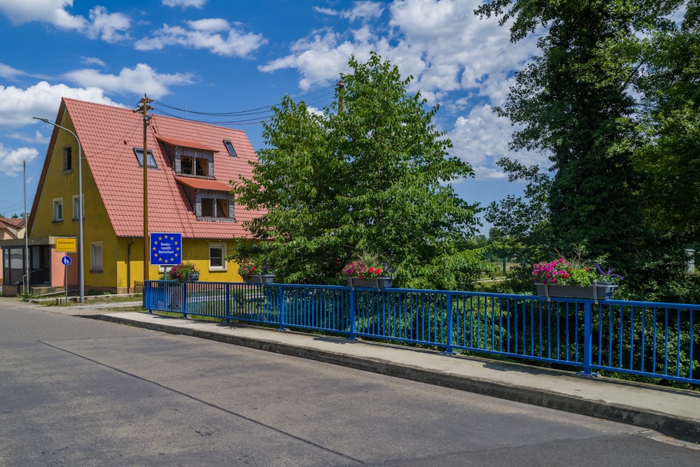 a street with a blue fence and trees on the side