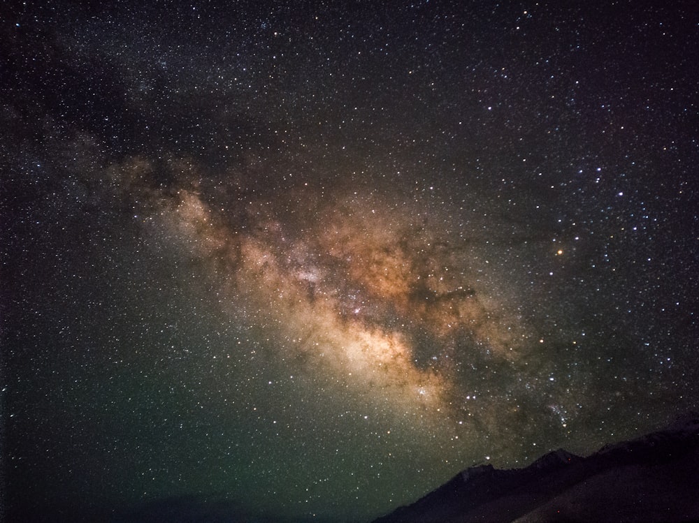 a starry night sky with a mountain and a mountain