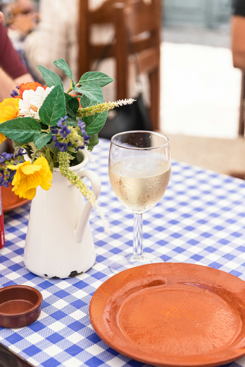 eine Vase mit Blumen und ein Glas Wein auf einem Tisch