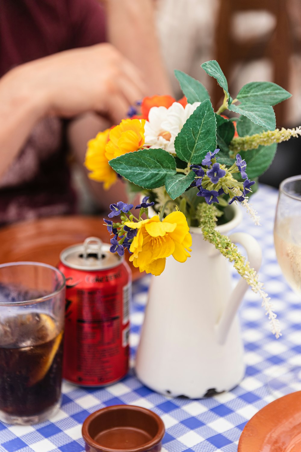 a vase with flowers and a can of beer on a table