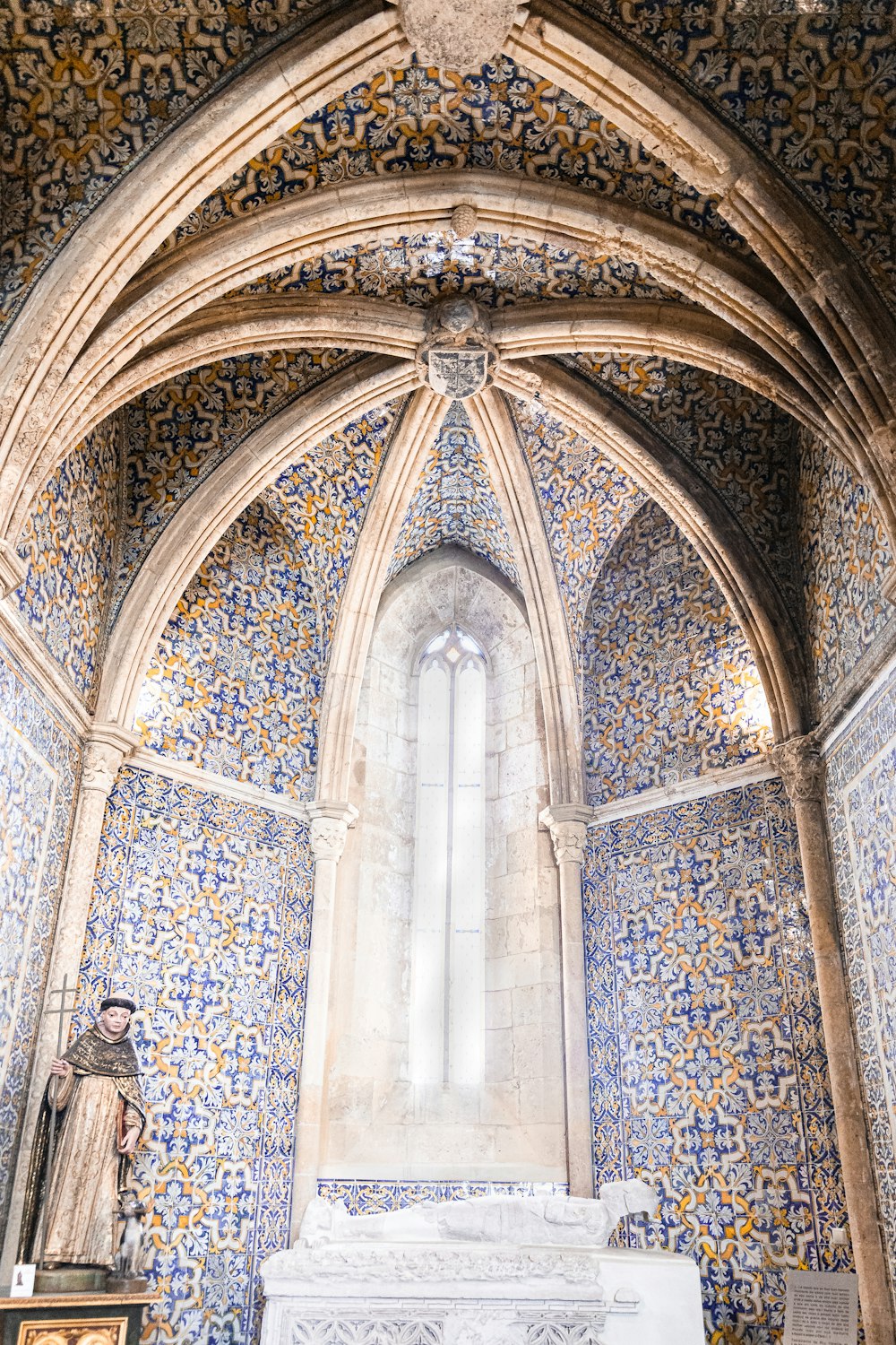 a statue in a room with a large ceiling and stained glass windows