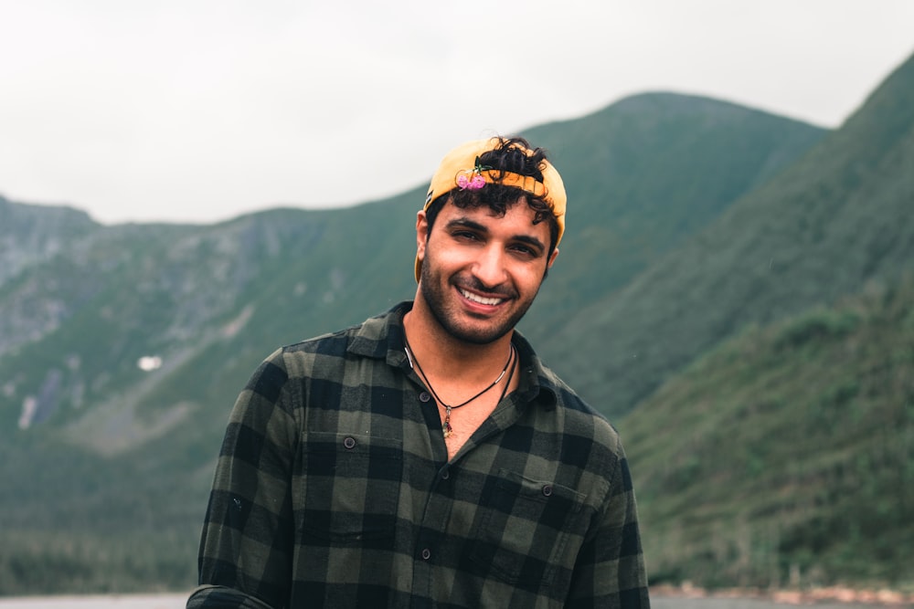 a man smiling with a mountain in the background