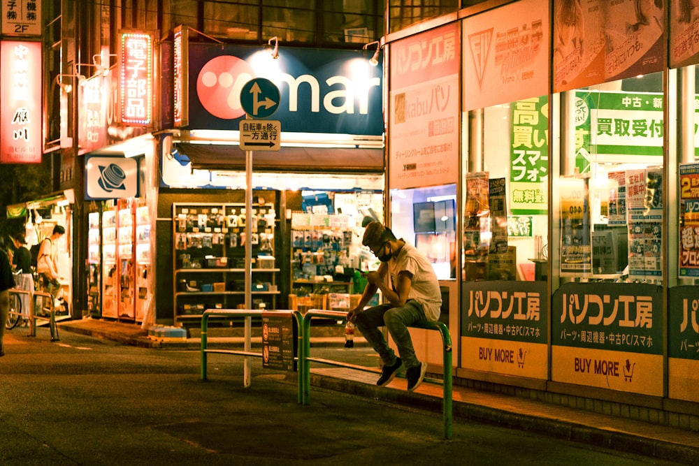 a person sitting on a bench in front of a storefront