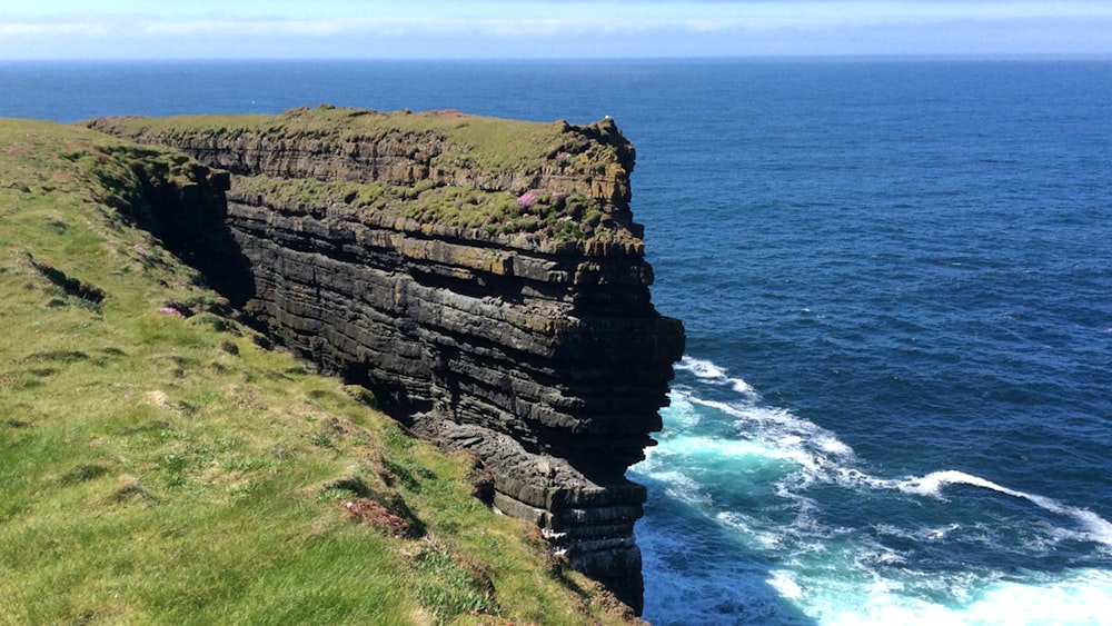 a cliff next to the ocean with Cliffs of Moher in the background