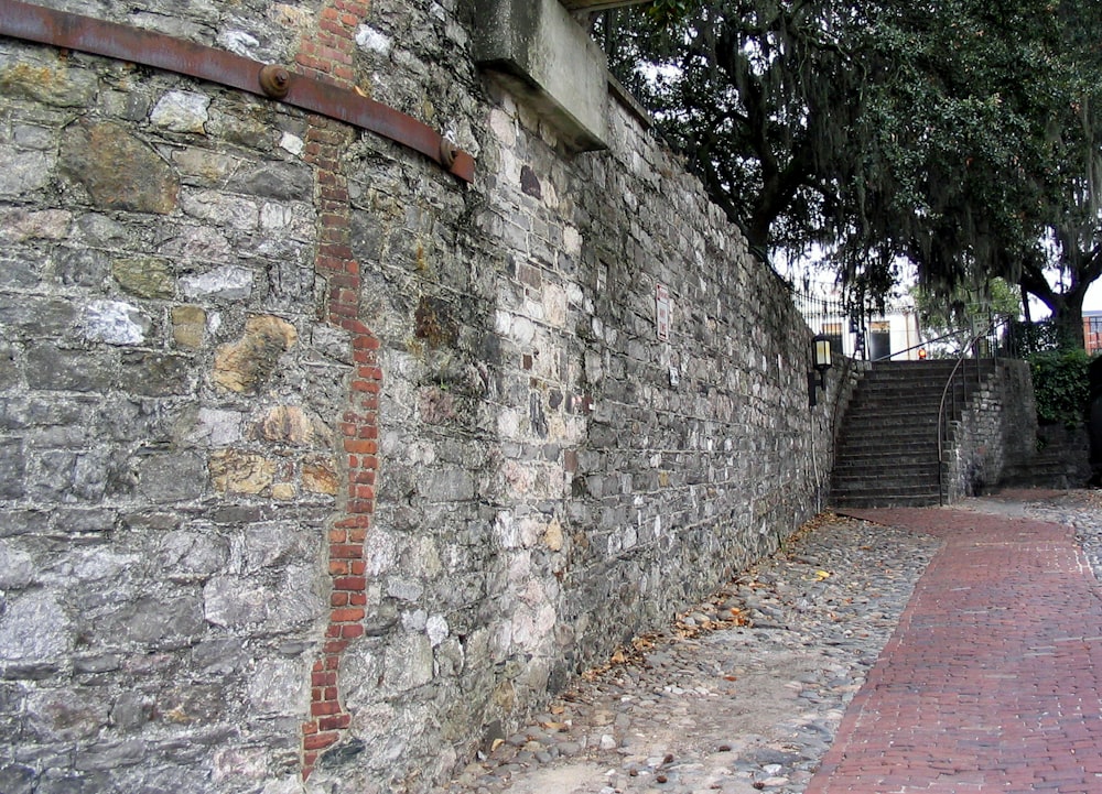a stone wall with a brick walkway