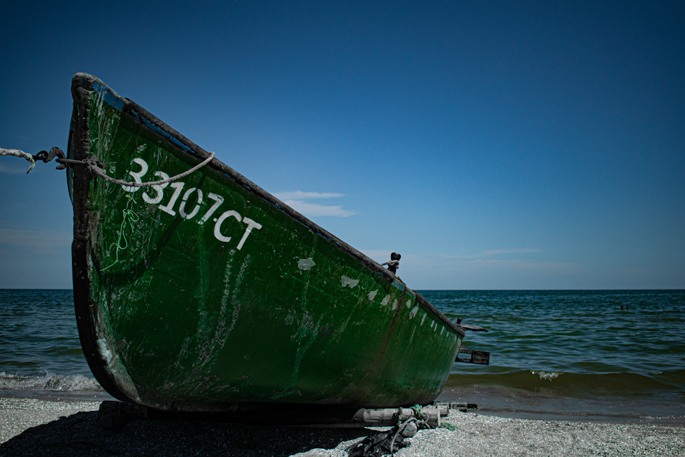 a large green boat on a beach